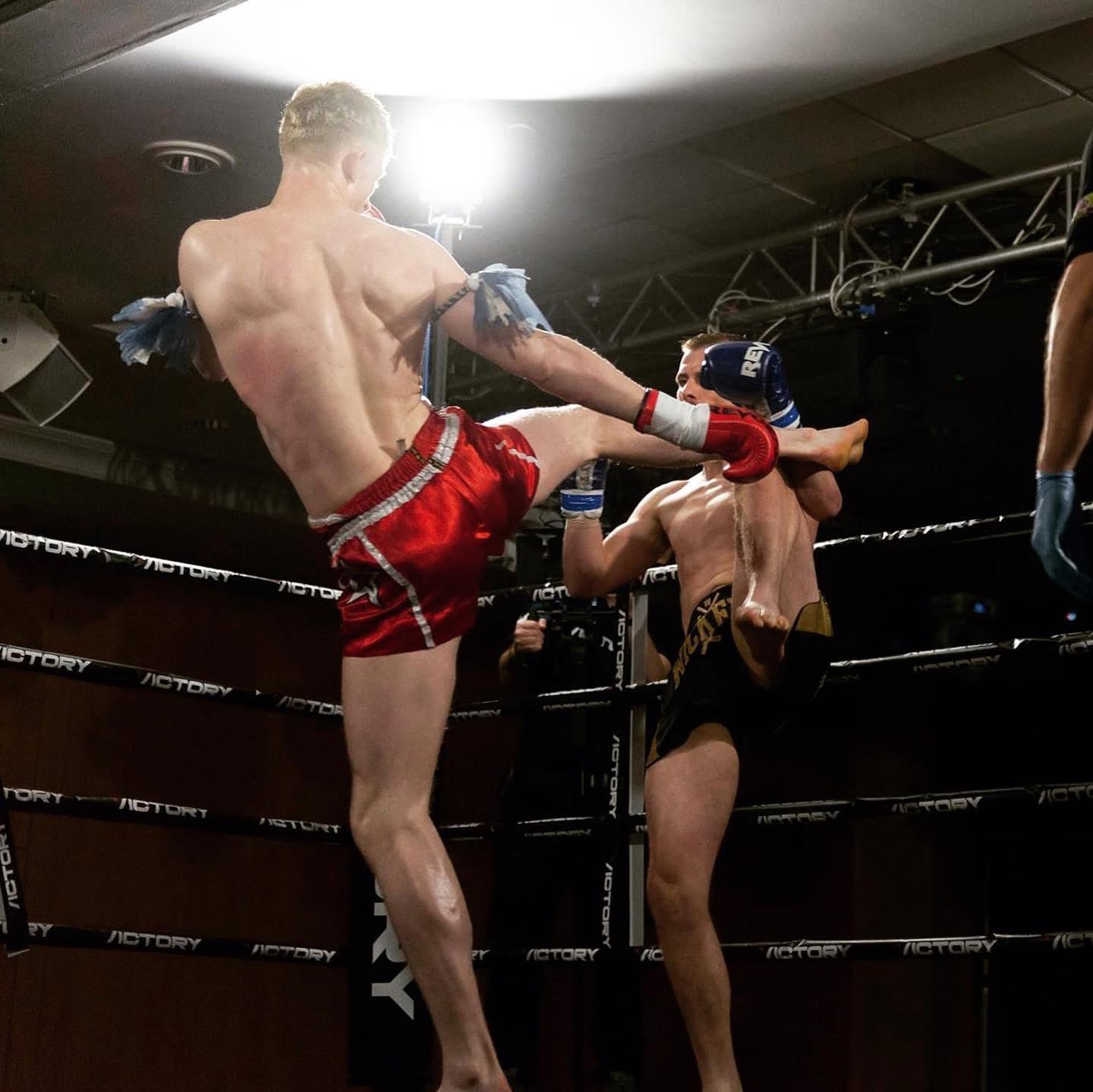 Alex MacGregor head kick in the ring wearing red Thai shorts