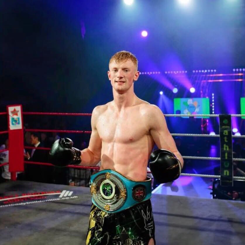 Alex MacGregor in the ring wearing a championship belt after a title win